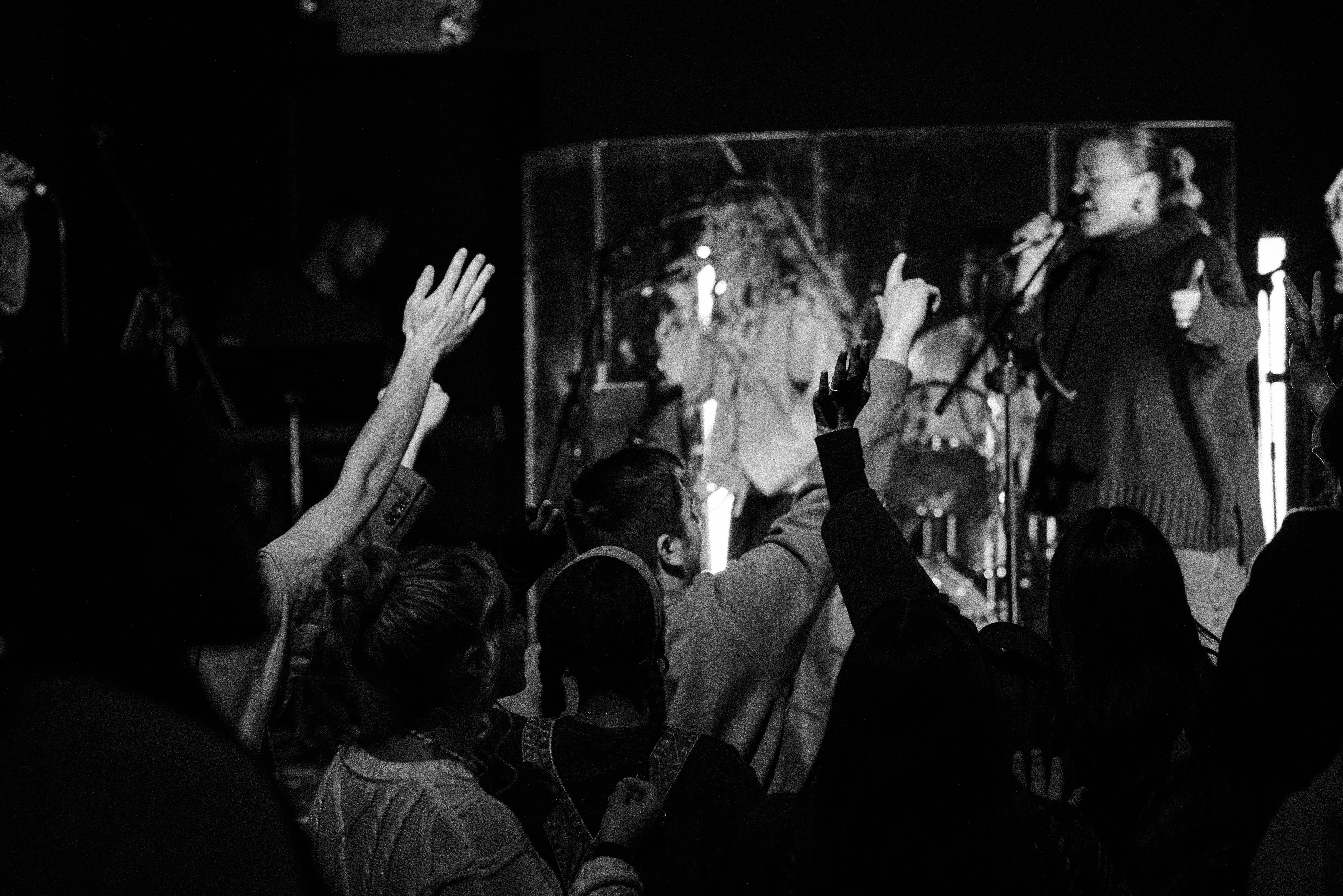 Worship team leading as hands go up across the room at Monday Nights