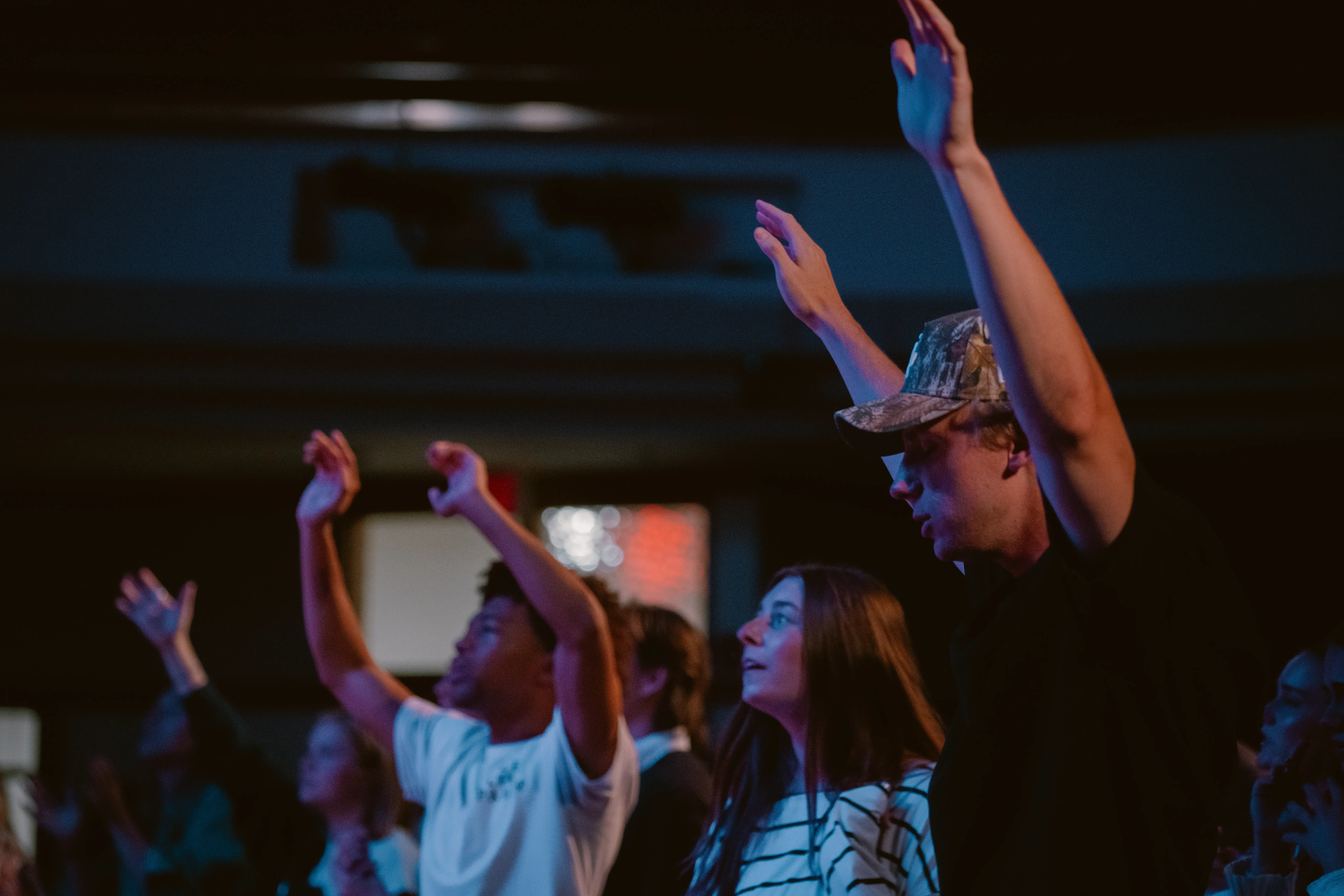 A generation of young people worshipping with hands raised at Monday Nights